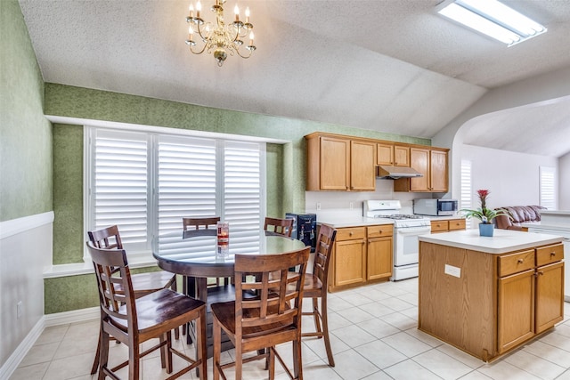 7012 Hillshire Ln, Sachse, TX 75048 - kitchen with white range with gas stovetop, under cabinet range hood, stainless steel microwave, lofted ceiling, and light countertops