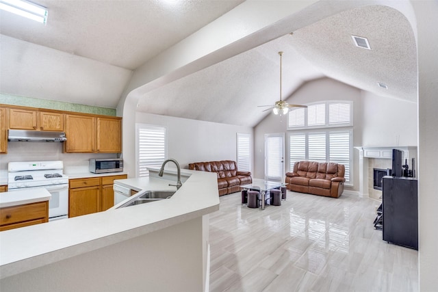 7012 Hillshire Ln, Sachse, TX 75048 - kitchen with gas range gas stove, under cabinet range hood, stainless steel microwave, light countertops, and open floor plan