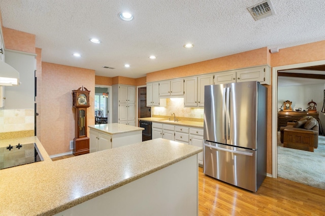 2815 Whisperwood Trl, Dalworthington Gardens, TX 76016 - kitchen featuring black appliances, a peninsula, light wood-style floors, a textured ceiling, and backsplash