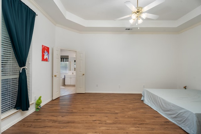 8479 Firewheel Ln, Frisco, TX 75036 - bedroom featuring a tray ceiling, wood finished floors, ceiling fan, and ensuite bathroom