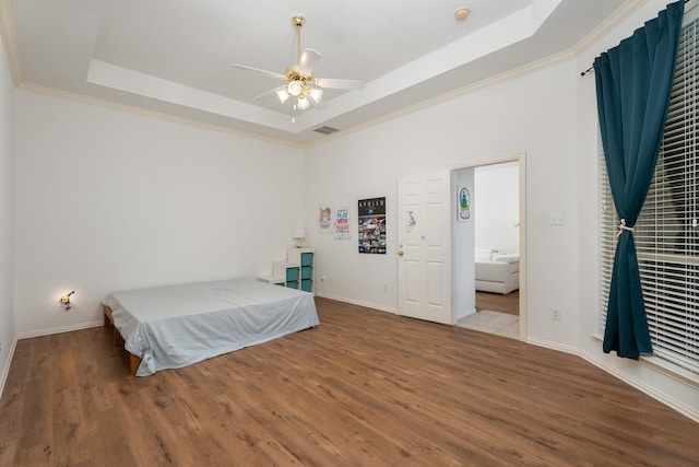 8479 Firewheel Ln, Frisco, TX 75036 - bedroom featuring a raised ceiling, wood finished floors, crown molding, and a ceiling fan