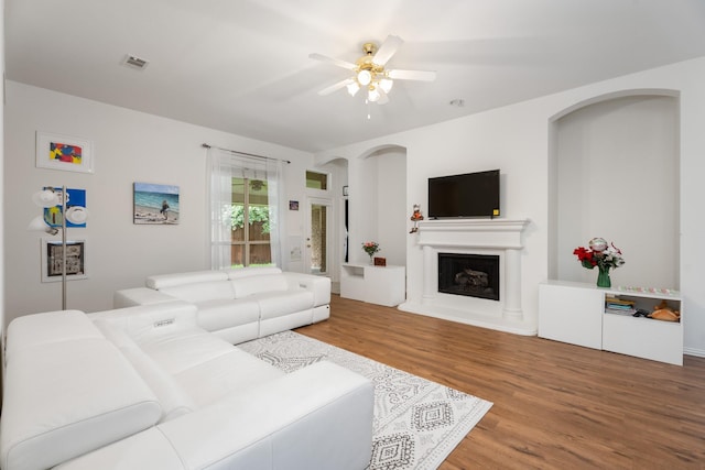 8479 Firewheel Ln, Frisco, TX 75036 - living area with wood finished floors, ceiling fan, arched walkways, and a fireplace with raised hearth