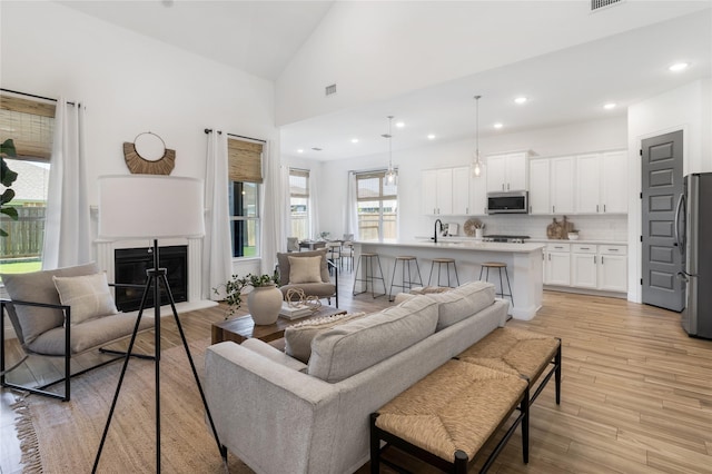 1604 Berry Ridge Trl, Aubrey, TX 76227 - living area with light wood-type flooring, a fireplace, high vaulted ceiling, and recessed lighting