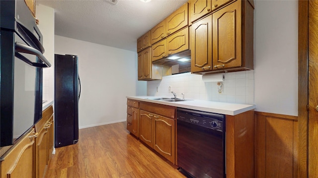 1550 Pamela Ln, Fort Worth, TX 76112 - kitchen featuring black appliances, light wood-style flooring, backsplash, light countertops, and brown cabinets
