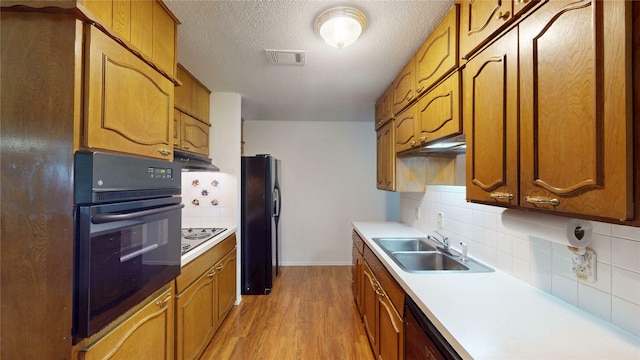 1550 Pamela Ln, Fort Worth, TX 76112 - kitchen with black appliances, tasteful backsplash, a textured ceiling, light wood finished floors, and light countertops