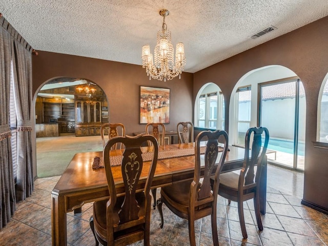 1425 Meyers Rd, Irving, TX 75060 - dining space featuring a chandelier, arched walkways, and a textured ceiling