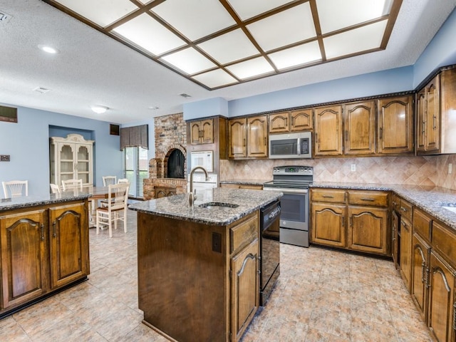 1425 Meyers Rd, Irving, TX 75060 - kitchen with appliances with stainless steel finishes, dark stone counters, a center island with sink, tasteful backsplash, and recessed lighting