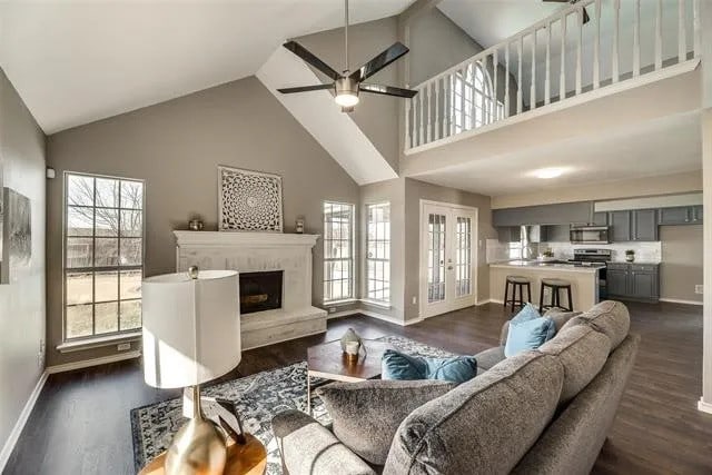 4914 Redwater Dr, Arlington, TX 76018 - living area with high vaulted ceiling, dark wood-type flooring, a ceiling fan, and a fireplace with raised hearth