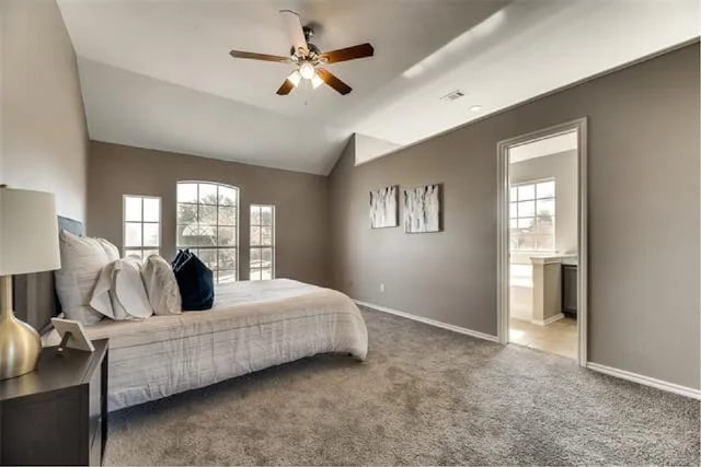 4914 Redwater Dr, Arlington, TX 76018 - carpeted bedroom featuring multiple windows, lofted ceiling, ensuite bath, and a ceiling fan