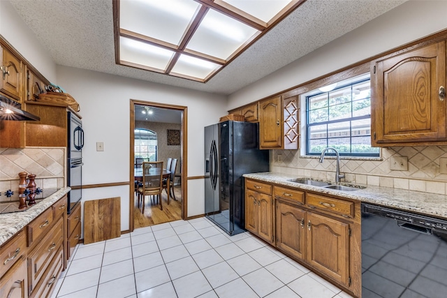 128 Timber Ridge Dr, Murphy, TX 75094 - kitchen featuring black appliances, backsplash, brown cabinetry, and a textured ceiling