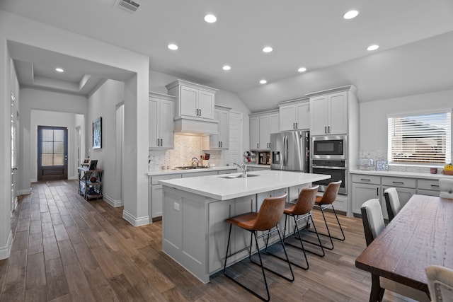 3700 Blue Stream Dr, Little Elm, TX 75068 - kitchen with stainless steel appliances, light countertops, tasteful backsplash, an island with sink, and dark wood finished floors