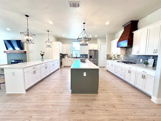 2402 Amesbury Dr, Midlothian, TX 76065 - kitchen with custom range hood, appliances with stainless steel finishes, a peninsula, backsplash, and light countertops