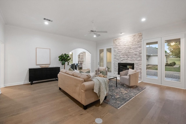 2800 Broadacres Ln, Dalworthington Gardens, TX 76016 - living room featuring light wood finished floors, arched walkways, a ceiling fan, a stone fireplace, and crown molding