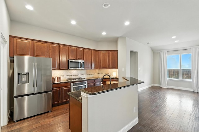 7508 Guadalupe Way, Mckinney, TX 75071 - kitchen featuring appliances with stainless steel finishes, tasteful backsplash, a center island with sink, dark wood-type flooring, and recessed lighting