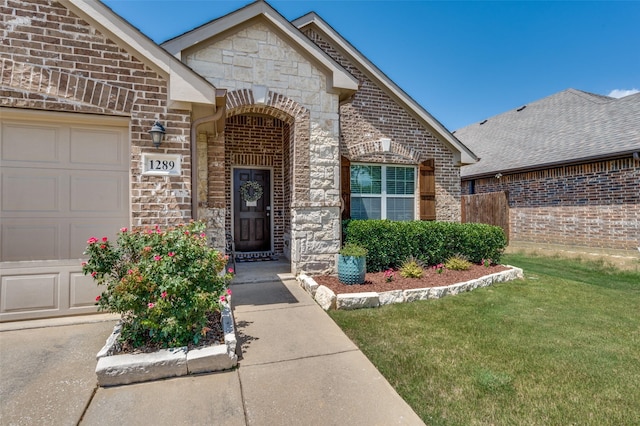 1289 Lasso Dr, Little Elm, TX 75068 - property entrance featuring stone siding, a garage, brick siding, and a lawn