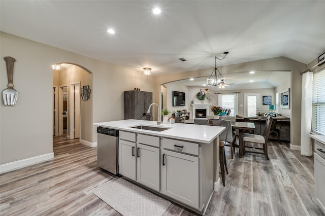 1289 Lasso Dr, Little Elm, TX 75068 - kitchen featuring stainless steel dishwasher, arched walkways, a fireplace, open floor plan, and light wood-type flooring