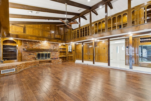 1605 Canyon Oaks Dr, Irving, TX 75061 - unfurnished living room with wood-type flooring, wood walls, ceiling fan, beam ceiling, and a brick fireplace