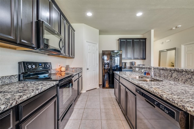 3133 Montserrat Creek Dr, Little Elm, TX 75068 - kitchen with black appliances, light stone countertops, light tile patterned floors, dark cabinets, and a textured ceiling