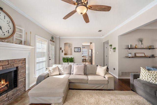 8571 Hidden Spring Dr, Frisco, TX 75034 - living room featuring ornamental molding, a ceiling fan, a stone fireplace, arched walkways, and wood finished floors