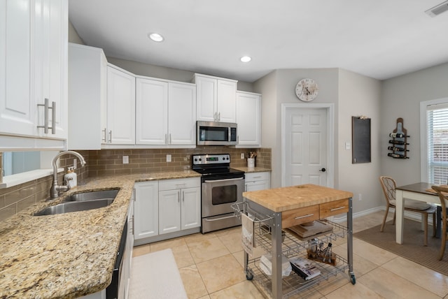 8571 Hidden Spring Dr, Frisco, TX 75034 - kitchen with appliances with stainless steel finishes, backsplash, white cabinetry, light tile patterned floors, and light stone countertops