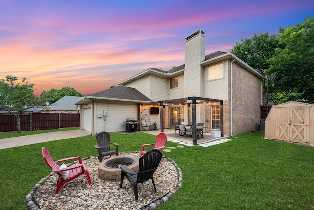 8571 Hidden Spring Dr, Frisco, TX 75034 - rear view of property featuring an outdoor fire pit, a storage unit, concrete driveway, a patio, and an attached garage