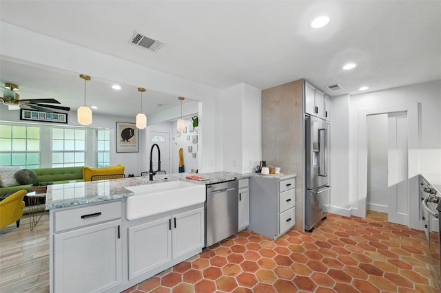 3056 Valley View Ln, Farmers Branch, TX 75234 - kitchen featuring stainless steel appliances, a peninsula, recessed lighting, pendant lighting, and light stone counters