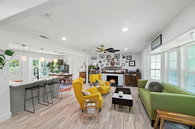 3056 Valley View Ln, Farmers Branch, TX 75234 - living room with light wood-style flooring, a warm lit fireplace, a ceiling fan, and recessed lighting