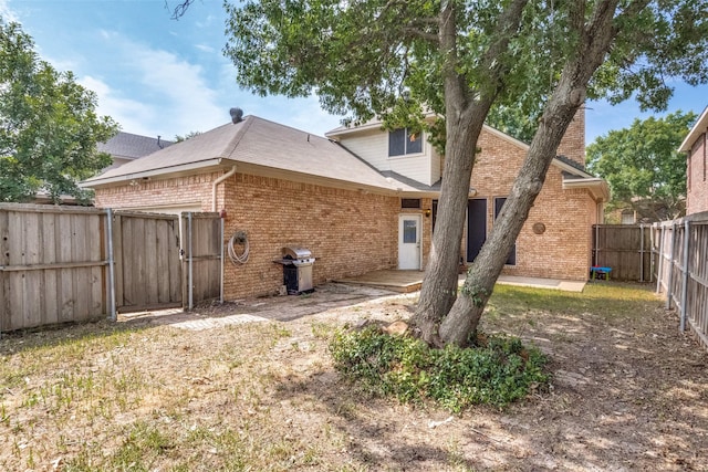 8813 Greenwood Trl, Rowlett, TX 75088 - back of house with brick siding, a fenced backyard, and a gate