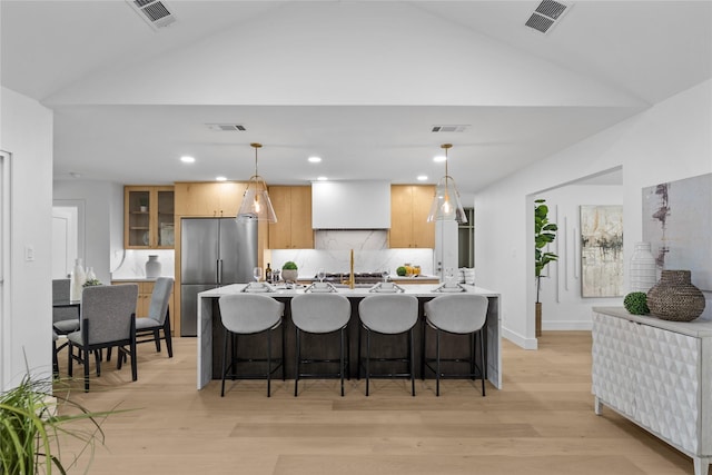 4408 Thunder Rd, Dallas, TX 75244 - kitchen featuring vaulted ceiling, light wood-style flooring, freestanding refrigerator, an island with sink, and a breakfast bar