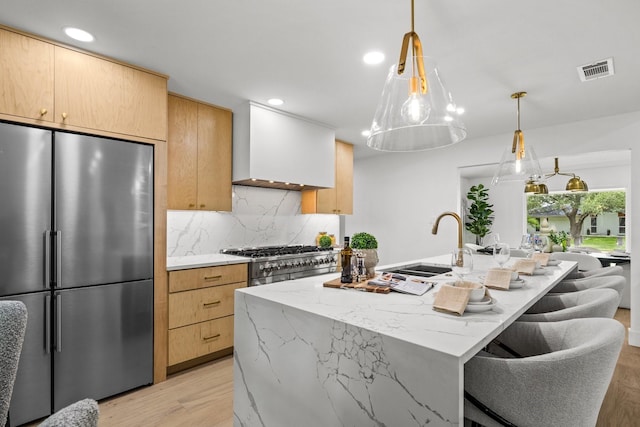 4408 Thunder Rd, Dallas, TX 75244 - kitchen with stainless steel appliances, light wood-style flooring, premium range hood, backsplash, and an island with sink