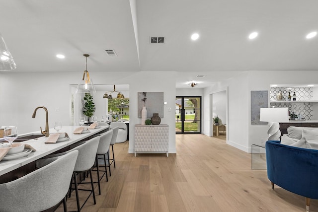 4408 Thunder Rd, Dallas, TX 75244 - kitchen featuring open floor plan, light wood-style floors, a kitchen bar, recessed lighting, and decorative backsplash