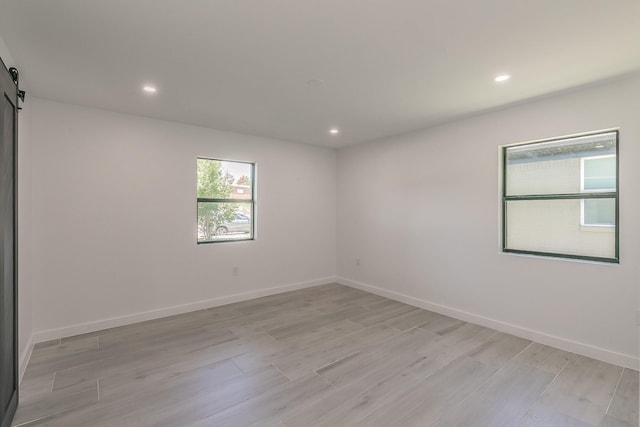 13516 Spring Grove Ave, Dallas, TX 75240 - spare room featuring recessed lighting, a barn door, and light wood-style floors