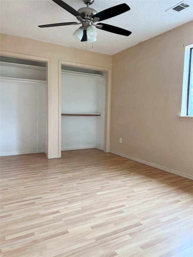 1429 Keisa Ln, Irving, TX 75060 - unfurnished bedroom with two closets, light wood-type flooring, a textured ceiling, and ceiling fan