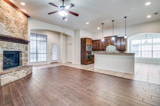 7611 Forest Ridge Trl, Sachse, TX 75048 - kitchen featuring appliances with stainless steel finishes, open floor plan, a ceiling fan, decorative backsplash, and arched walkways
