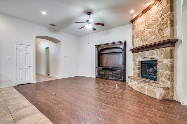 7611 Forest Ridge Trl, Sachse, TX 75048 - unfurnished living room featuring arched walkways, a ceiling fan, wood finished floors, and a fireplace