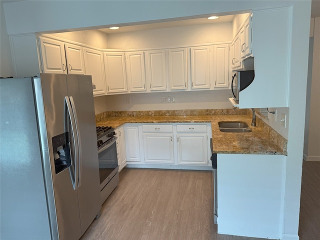 4005 Tacoma St, Irving, TX 75062 - kitchen featuring appliances with stainless steel finishes, stone counters, white cabinets, light wood-style flooring, and recessed lighting