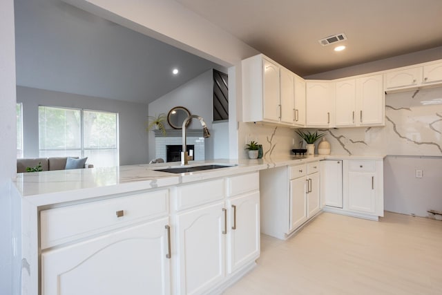 947 Aspen Dr, Desoto, TX 75115 - kitchen with a peninsula, a brick fireplace, decorative backsplash, white cabinets, and recessed lighting