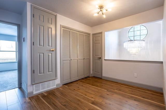 947 Aspen Dr, Desoto, TX 75115 - unfurnished bedroom with a chandelier, wood finished floors, and a closet