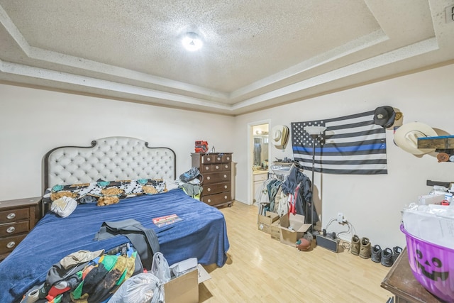 3612 Hummingbird Ave, Mcallen, TX 78504 - bedroom featuring a tray ceiling, light wood-type flooring, a textured ceiling, and connected bathroom