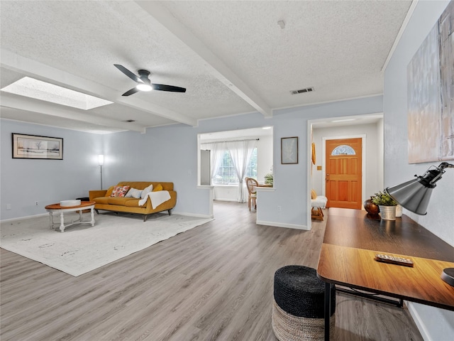 2012 Westlake Dr, Plano, TX 75075 - living area featuring a textured ceiling, a ceiling fan, wood finished floors, beamed ceiling, and a skylight