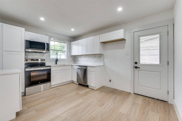 2504 Wicker Ave, Farmers Branch, TX 75234 - kitchen with stainless steel appliances, light wood finished floors, white cabinetry, tasteful backsplash, and recessed lighting
