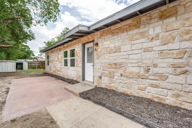 2504 Wicker Ave, Farmers Branch, TX 75234 - view of exterior entry with stone siding and a patio