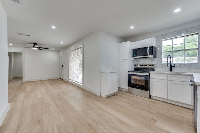 2504 Wicker Ave, Farmers Branch, TX 75234 - kitchen with stainless steel appliances, light wood finished floors, white cabinetry, and recessed lighting