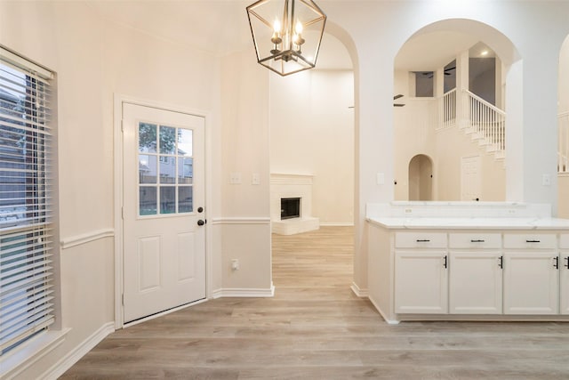 5920 Colby Dr, Plano, TX 75094 - kitchen featuring white cabinets, light wood finished floors, a chandelier, a high ceiling, and a fireplace