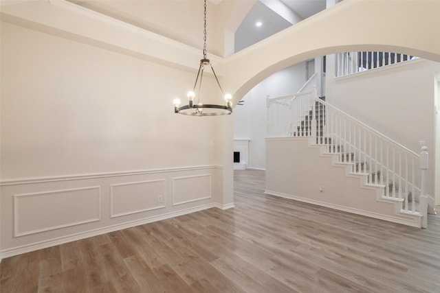 5920 Colby Dr, Plano, TX 75094 - unfurnished dining area featuring a high ceiling, a chandelier, wood finished floors, stairway, and arched walkways