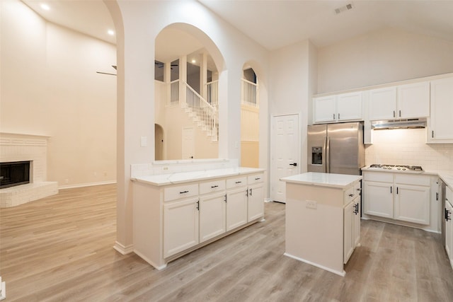 5920 Colby Dr, Plano, TX 75094 - kitchen featuring stainless steel fridge, under cabinet range hood, high vaulted ceiling, decorative backsplash, and white cabinetry