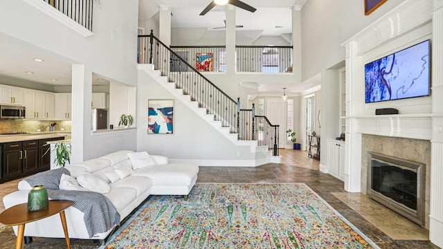 2945 Horseshoe Trl, Frisco, TX 75033 - living area featuring a high ceiling, stairs, ceiling fan, a high end fireplace, and dark stone finish flooring