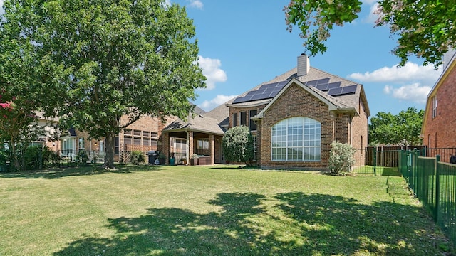 2945 Horseshoe Trl, Frisco, TX 75033 - back of property with brick siding, a chimney, roof mounted solar panels, a fenced backyard, and roof with shingles