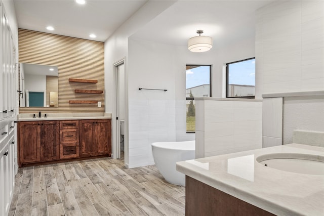 2910 Eagles Nest Ct, Midlothian, TX 76065 - bathroom with vanity, a freestanding bath, wood finished floors, recessed lighting, and tile walls