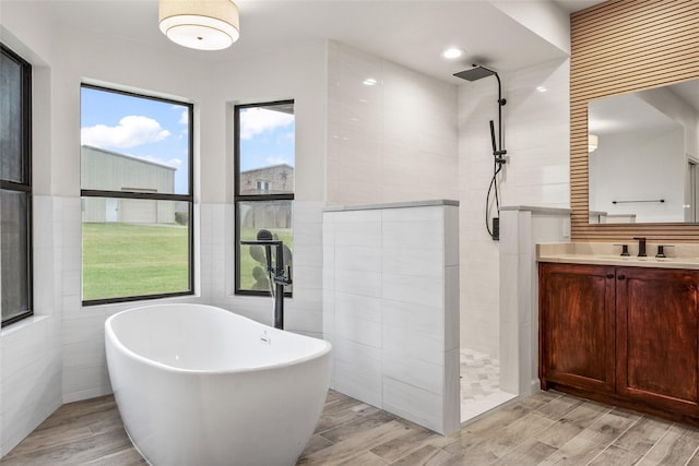 2910 Eagles Nest Ct, Midlothian, TX 76065 - bathroom with a walk in shower, wood finished floors, a soaking tub, vanity, and tile walls